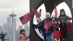 シアトルの子どものワークショップのメンバーは就任式を祝うために作った旗を持ち彫刻の中でポーズ