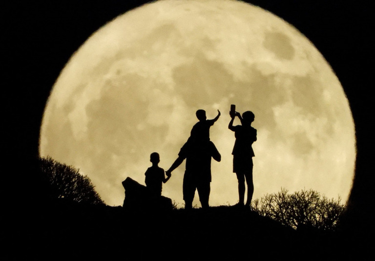 満月を眺める家族連れ＝８月１日、スペインのグラン・カナリア島/Borja Suarez/Reuters
