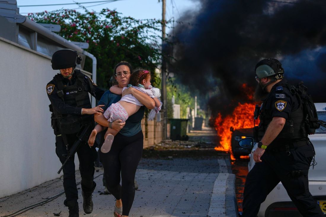 子どもと女性の避難を助ける警官＝１０月７日、イスラエル・アシュケロン/Tsafrir Abayov/AP