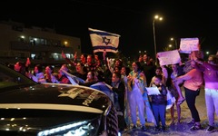 解放された人質を運んできた車両を歓迎する人々＝１１月２６日、イスラエル・オファキム