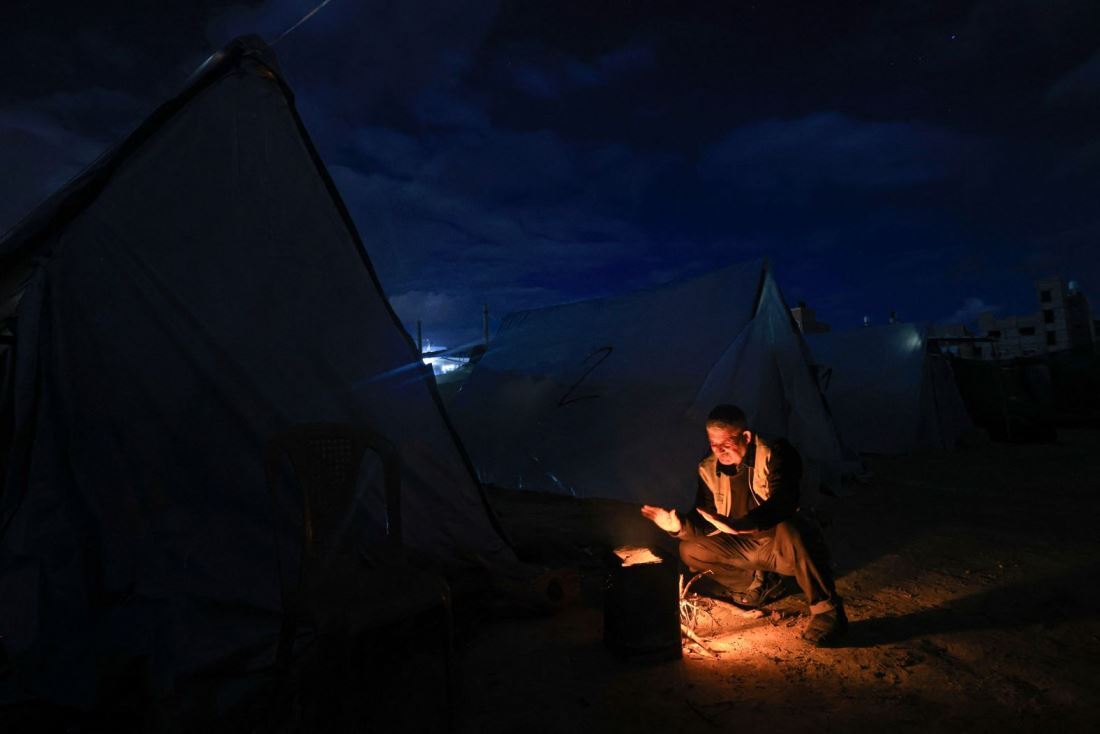 家を追われ避難先のテントで暖を取る男性＝１１月２７日、パレスチナ自治区ガザ地区ハンユニス/Mahmud Hams/AFP/Getty Images