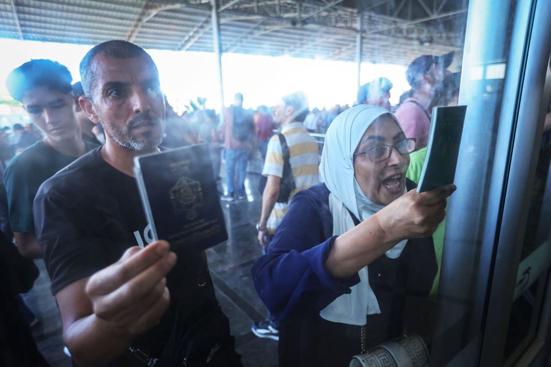 パレスチナ自治区ガザ地区とエジプトを結ぶラファ検問所から避難するためパスポートを示す人たち＝１１月１日/Ahmad Salem/Bloomberg/Getty Images