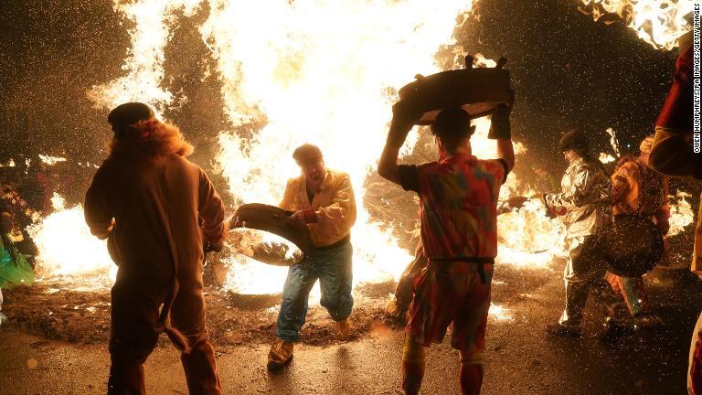 燃えるウイスキーのたるを運ぶ男性ら＝イングランド/Owen Humphreys/PA Images/Getty Images