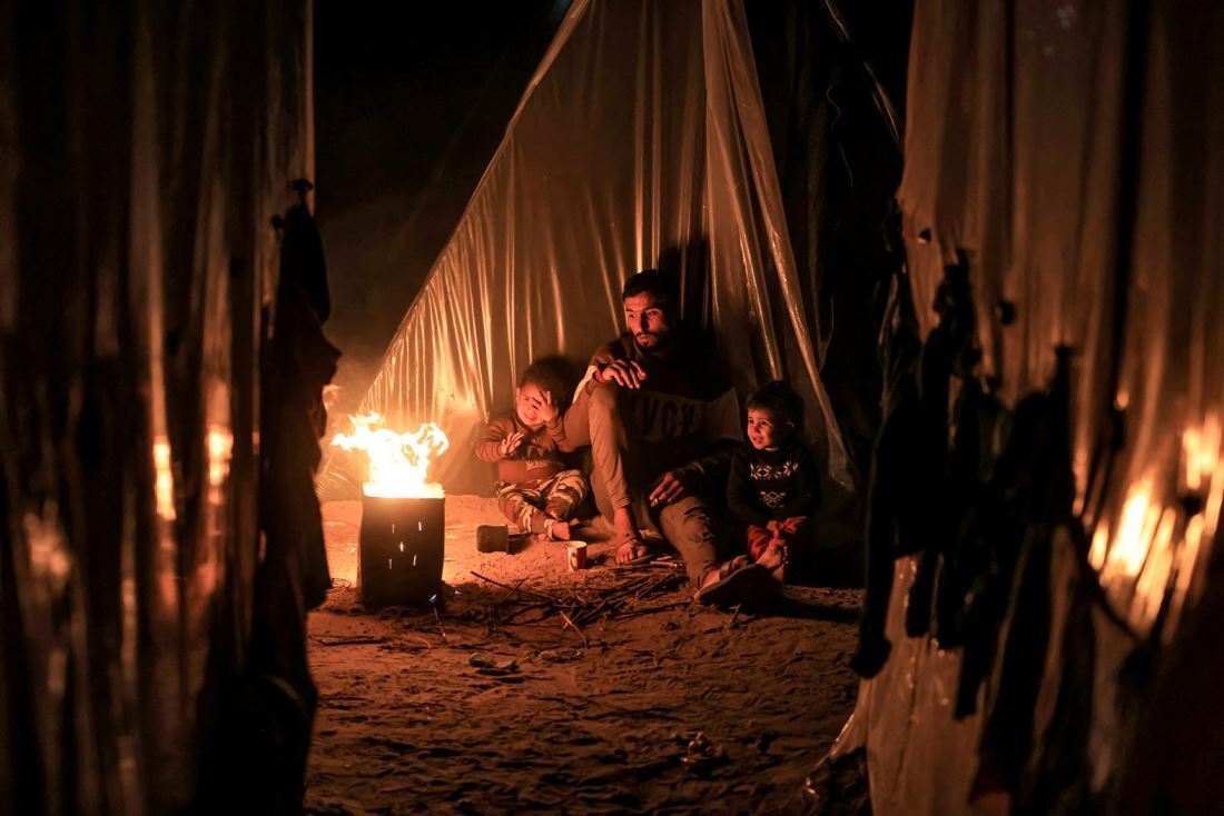 子どもと火にあたる男性＝１２月１８日、パレスチナ自治区ガザ地区ラファ/Mahmud Hams/AFP/Getty Images