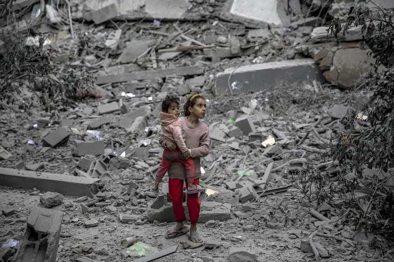 子どもを抱いて歩く少女＝３日、パレスチナ自治区ガザ地区ガザ市/AFP/Getty Images