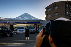 富士河口湖町のコンビニの前で遠景の富士山を撮影する観光客