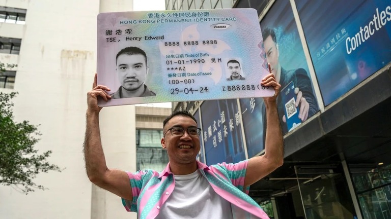 男性と明示された身分証に見立てたプラカードを掲げる活動家、ヘンリー・ツェさん/Vernon Yuen/AP